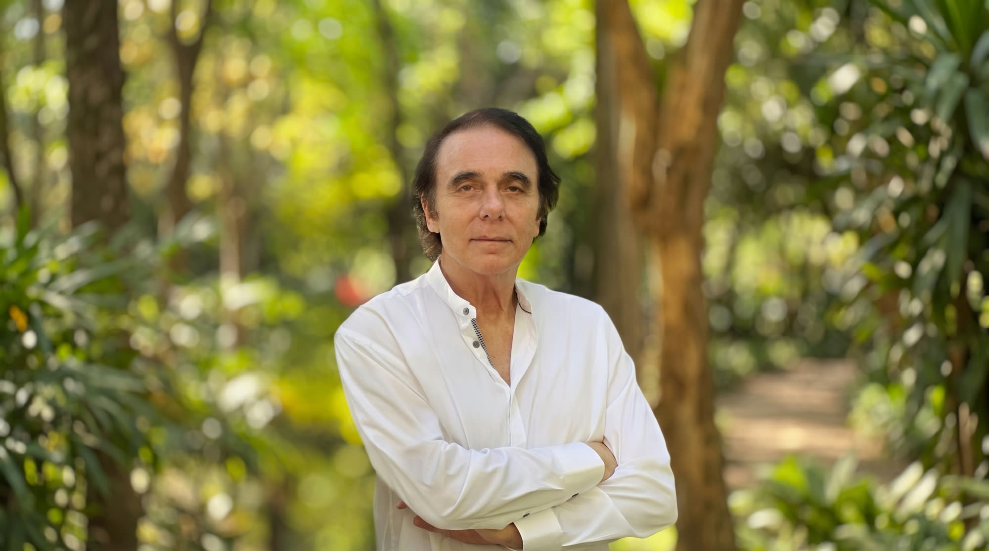 Dr. Thomas Lodi standing outdoors, arms crossed, white mandarin-collar shirt